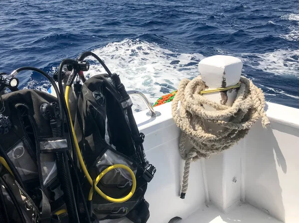 Hortum ve dalış ceketleri ile siyah dalış takım bir sürü stand ve hızlı hareketli tekne, gemi, mavi denize karşı tropikal bir tesis Cruise liner üzerinde ağır bir halat asmak.