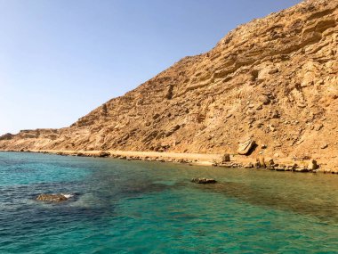 Büyük bir güzel görkemli taş kumlu dağ, bir höyük, bir tepe, mavi gökyüzüne karşı çölde bir tepe ve tuz yeşil Azure suları ve deniz. Manzara.