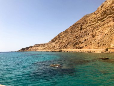 Büyük bir güzel görkemli taş kumlu dağ, bir höyük, bir tepe, mavi gökyüzüne karşı çölde bir tepe ve tuz yeşil Azure suları ve deniz. Doğal tropikal peyzaj.