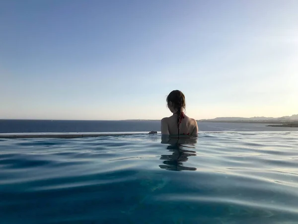 수영복을 수영을 아름다운 날씬한 소녀가 따뜻한 리조트에서 바다의 배경에 수평선과 — 스톡 사진