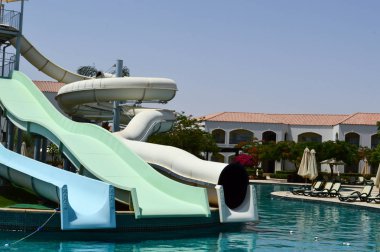 Bir tropikal sıcak egzotik ülkede tatilmavi berrak ılık su ve su kaydırak boruları ile açık yüzme havuzu, bir aquapark ile bir sahil beldesi.