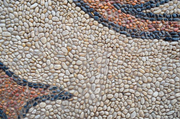 De textuur van de stenen muur, de weg van kleine ronde en ovale stenen met abstracte lijnen aangelegd patronen van zandstrand naden van natuurlijke oude geel zwart bruin. De achtergrond — Stockfoto