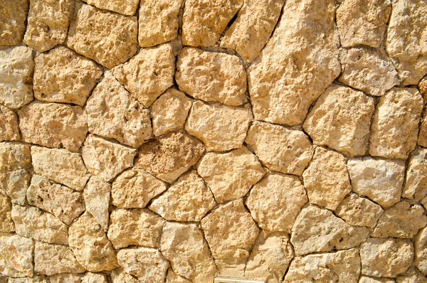 Textura de un muro de piedra, caminos de piedras, ladrillos, adoquines, baldosas con costuras arenosas de color gris antiguo natural amarillo antiguo con bordes afilados. El trasfondo — Foto de Stock