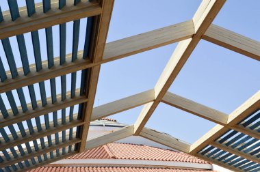 Ahşap çatı panoları ile kiriş ve arka plan mavi gökyüzüne karşı kırmızı taşlarla döşenmiş bir çatı üzerinde delik ile güneşten modern