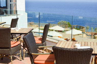 Hasır sandalyeleri ile denize karşı sokakta açık bir kafe ve tatil beldesi üzerinde sıcak bir tropikal ülkede ahşap masa görünümü