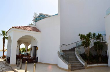 Palmiye ağaçları mavi deniz karşı istirahat bir sıcak tropikal egzotik Güney resort üzerinde kırmızı kiremit çatılı bina büyük bir sağlam beyaz Beton taş