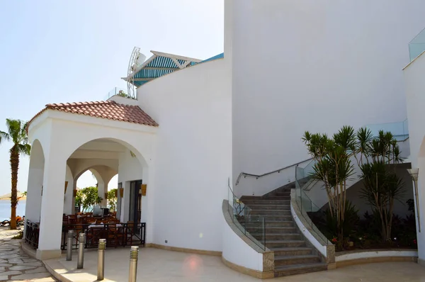 Duży kamień beton biały solidny budynek z dachem czerwony dachówka na ciepły tropikalny egzotyczne Południowej ośrodek odpoczynku przed błękitne morze palmy — Zdjęcie stockowe