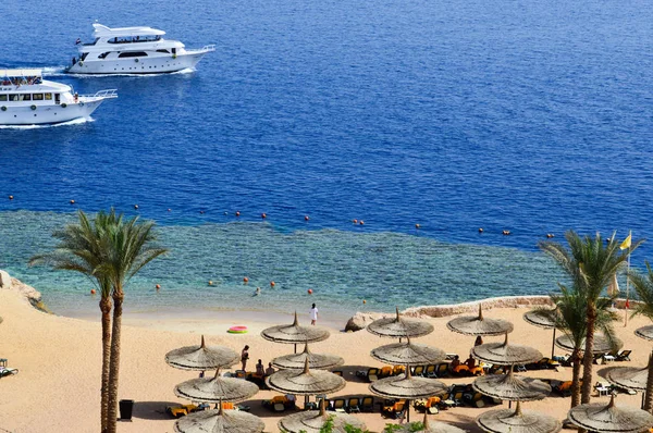 Vista superior de una playa de arena con tumbonas y sombrillas y dos grandes barcos blancos, un barco, un crucero flotando en el mar de vacaciones en un país tropical exótico cálido, un balneario — Foto de Stock