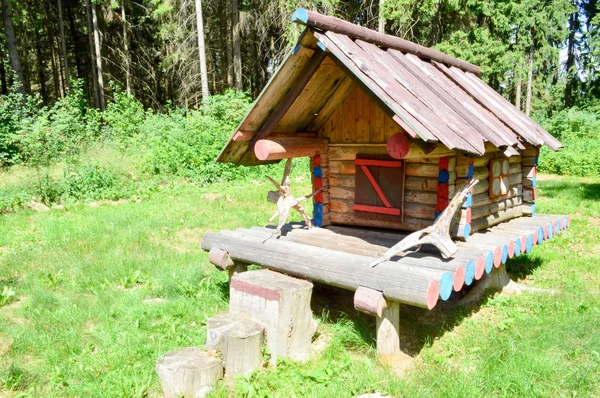 Pequena casa de cabana velha ramshackle de madeira em uma floresta de troncos de tábuas no fundo de árvores — Fotografia de Stock