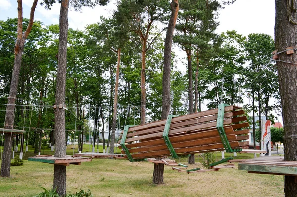 A climbing wall, trolls and a rope park are sporting for games and entertainment from boards and trees with ropes for playing children and adults in the woods in nature — Stock Photo, Image