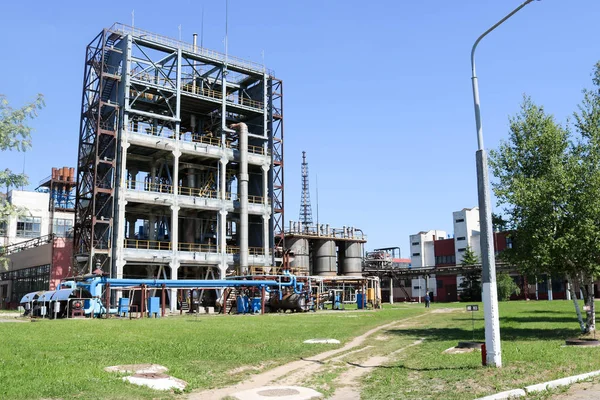 A large concrete technological industrial installation at a chemical petrochemical refinery with capacitive pipes by pumps compressors heat exchangers by pipelines and buildings — Stock Photo, Image