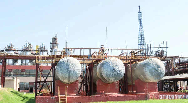 En stor metalliskt järn pipeline arbetsbock med rör och ledningar för elektricitet i en petrokemisk kemisk raffinaderi i bakgrunden av skal-och-rör värmeväxlare och utrustning — Stockfoto
