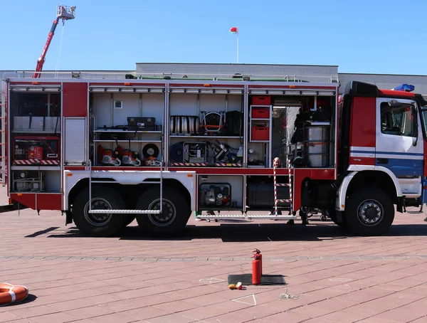 Великий спеціальний червоний з синім пожежним автомобілем, двигун для порятунку людей з відкритими боками і гасіння обладнання, пожежний насос, дме агент, інструмент, водяні рукави, шланги, балончики, обладнання — стокове фото