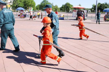 Bir itfaiyeci adam biraz Belarus, Minsk, 08.08.2018 söndürmek için hortumlar ile koşmaya kalitesiz bir yanmaz elbise kız gözenekleri öğretiyor