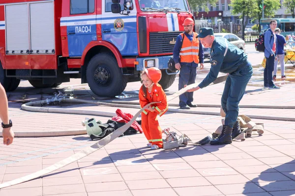 Людина пожежного викладання трохи дівчина у вогнетривкій злісного костюм бігати шлангові гасити пори Білорусь, Мінськ, 08.08.2018 — стокове фото