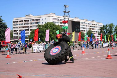 Bir itfaiyeci yanmaz bir takım elbise içinde çalışır ve rekabet, Belarus, Minsk, 08.08.2018 mücadele yangında büyük lastik tekerlek dönüyor
