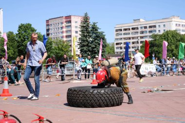 Bir itfaiyeci yanmaz bir takım elbise içinde çalışır ve rekabet, Belarus, Minsk, 08.08.2018 mücadele yangında büyük lastik tekerlek dönüyor