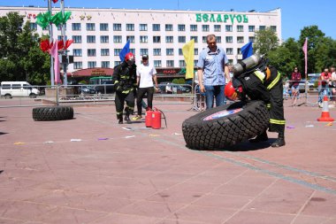 Bir itfaiyeci yanmaz elbise giyip kask içinde çalışır ve rekabet, Belarus, Minsk, 08.08.2018 mücadele yangında büyük lastik tekerlek dönüyor