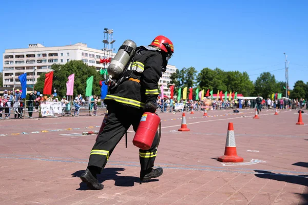 Пожежник у вогнетривкому костюмі і шолом біжить з червоними вогнегасниками, щоб загасити вогонь — стокове фото