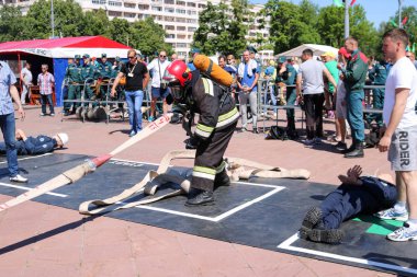 Bir itfaiyeci yanmaz bir takım elbise ve bir oksijen balon çekerek ile çalışan, bir yangın hortumu bir yangın spor Yarışması'nda tutan bir kask. Minsk, Beyaz Rusya, 08.07.2018