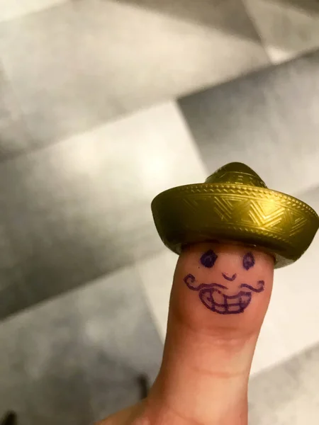 Palec, prst mexické sombrero Zlatá čepice s malovanými veselá Veselý obličej s kníry a očima — Stock fotografie