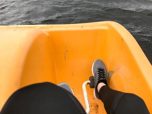 穿灰色运动鞋的腿在黄色双体船上靴踏板 — 图库照片