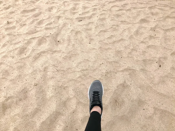 O pé no sapato cinza da bota faz um passo contra o fundo de uma areia natural solta amarela dourada bonita praia quente — Fotografia de Stock