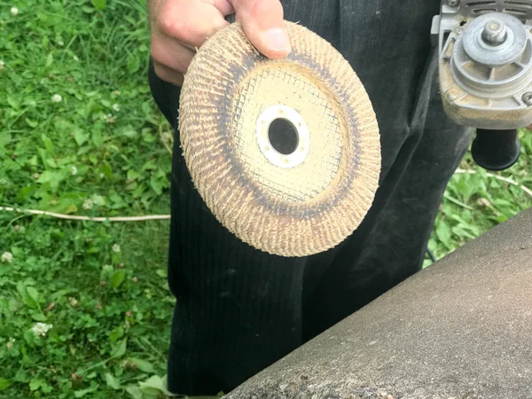 Ein Mann hält eine Scheibe eines Kreises in der Hand, die für eine Schleifmaschine zum Schleifen und Polieren von Oberflächen aus verschiedenen Materialien verwendet wird: Holz, Metall, Kunststoff, Stein — Stockfoto