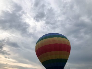 Büyük çok renkli parlak yuvarlak gökkuşağı renkli şeritli çizgili uçan balon ile akşam gökyüzünde karşı bir sepet