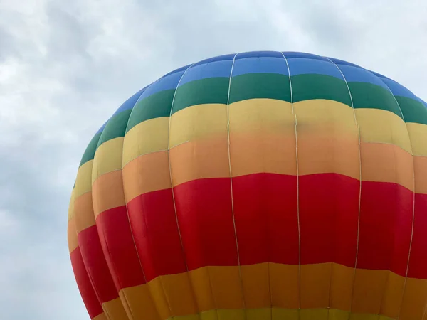 Große bunte helle runde regenbogenfarbene gestreifte fliegende Ballons mit einem Korb gegen den Himmel am Abend — Stockfoto