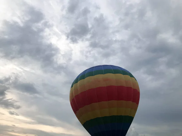 Große bunte helle runde regenbogenfarbene gestreifte fliegende Ballons mit einem Korb gegen den Himmel am Abend — Stockfoto