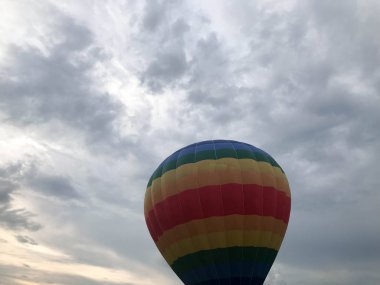 Büyük çok renkli parlak yuvarlak gökkuşağı renkli şeritli çizgili uçan balon ile akşam gökyüzünde karşı bir sepet