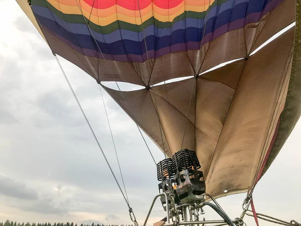 Velké silné kovové železo hořáky, tepelné fény s ohněm, aby teplo horkovzdušným ve velkém mnohobarevný světlé kulaté duha barevné pruhované létající balón. Na pozadí — Stock fotografie