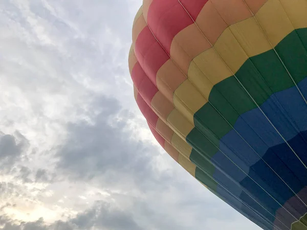 Große bunte helle runde regenbogenfarbene gestreifte fliegende Ballons mit einem Korb gegen den Himmel am Abend — Stockfoto