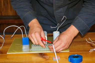 Elektrikçi çalışır, çalışan bir erkeğin toplar telleri ile büyük bir beyaz sokak lambası, bir geçiş bir endüstriyel tesis Fabrikası'nda elektrik devresi.