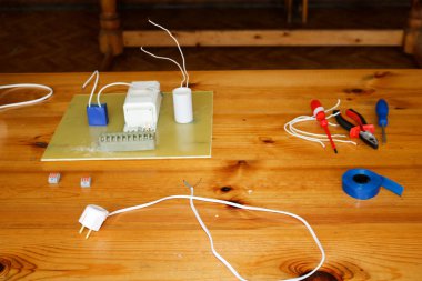 Teller ve yedek parça, montaj donatım, pense, mavi elektrik bandı, masada tornavidalar ile elektrik devresi