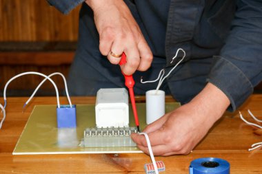 Elektrikçi çalışır, çalışan bir erkeğin toplar telleri ile büyük bir beyaz sokak lambası, bir geçiş bir endüstriyel tesis Fabrikası'nda elektrik devresi