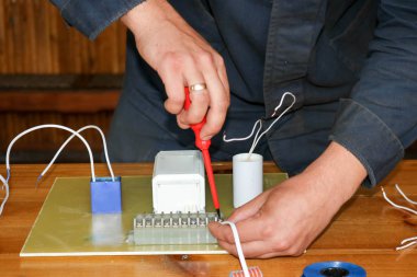 Elektrikçi çalışır, çalışan bir erkeğin toplar telleri ile büyük bir beyaz sokak lambası, bir geçiş bir endüstriyel tesis Fabrikası'nda elektrik devresi