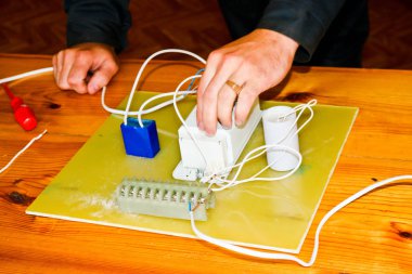 Elektrikçi çalışır, çalışan bir erkeğin toplar telleri ile büyük bir beyaz sokak lambası, bir geçiş bir endüstriyel tesis Fabrikası'nda elektrik devresi