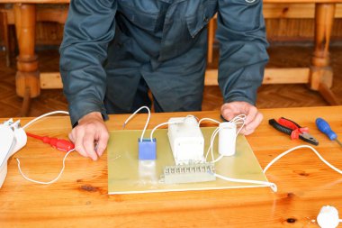 Elektrikçi çalışır, çalışan bir erkeğin toplar telleri ile büyük bir beyaz sokak lambası, bir geçiş bir endüstriyel tesis Fabrikası'nda elektrik devresi