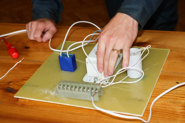 Elektrikçi çalışır, çalışan bir erkeğin toplar telleri ile büyük bir beyaz sokak lambası, bir geçiş bir endüstriyel tesis Fabrikası'nda elektrik devresi