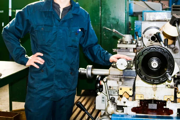 Kesme, bıçak metaller, ahşap ve diğer malzemeler, dönüm, Ayrıntılar ve fabrikada yedek parçalar yapma dönüm bir elbise içinde çalışan bir erkeğin bir endüstriyel Torna için yanında tulum standları