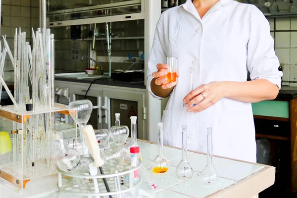 Een vrouwelijke laboratorium-assistent, een arts, een chemicus werken met kolven, reageerbuisjes, maakt oplossingen, medicijnen, mixen van de ingrediënten in het laboratorium. Laboratorium assistent voert het onderzoek uit — Stockfoto