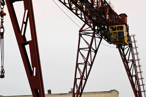 Grúa pórtico metálica grande de hierro industrial con un gancho montado en los soportes para levantar y transportar cargas pesadas, moviéndose a lo largo de los rieles de la fábrica. La grúa es de tipo puente —  Fotos de Stock