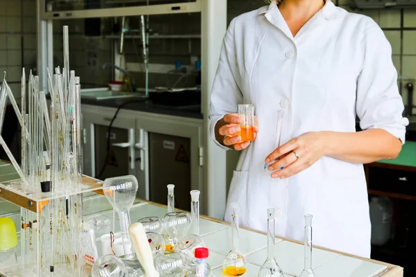 A female laboratory assistant, a doctor, a chemist, works with flasks, test tubes, makes solutions, medicines, mixes the ingredients in the laboratory. Laboratory assistant carries out the research — Stock Photo, Image