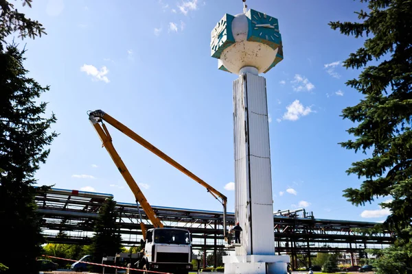 Repair of the tower clock. Workers on the crane repair clock-column, clock on the tower, paint, update, perform cosmetic repairs