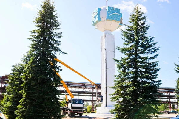 Repair of the tower clock. Workers on the crane repair clock-column, clock on the tower, paint, update, perform cosmetic repairs