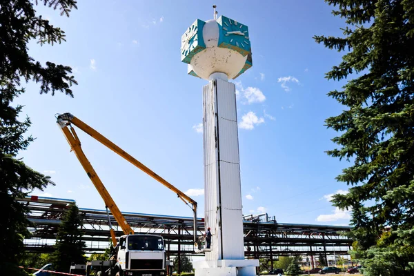 Repair of the tower clock. Workers on the crane repair clock-column, clock on the tower, paint, update, perform cosmetic repairs