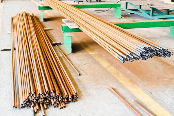 Almacén, un depósito de tubos oxidados delgados largos de hierro metálico en una planta industrial metalúrgica petroquímica — Foto de Stock