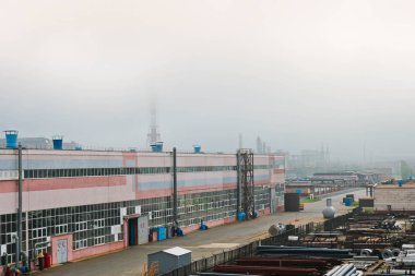 Endüstriyel manzara. Panoramik teknolojik borular. Paslı boruları, mavi yakut, üretim iletişim. Üretim binalar tamir. Puslu bir gökyüzü arka planı